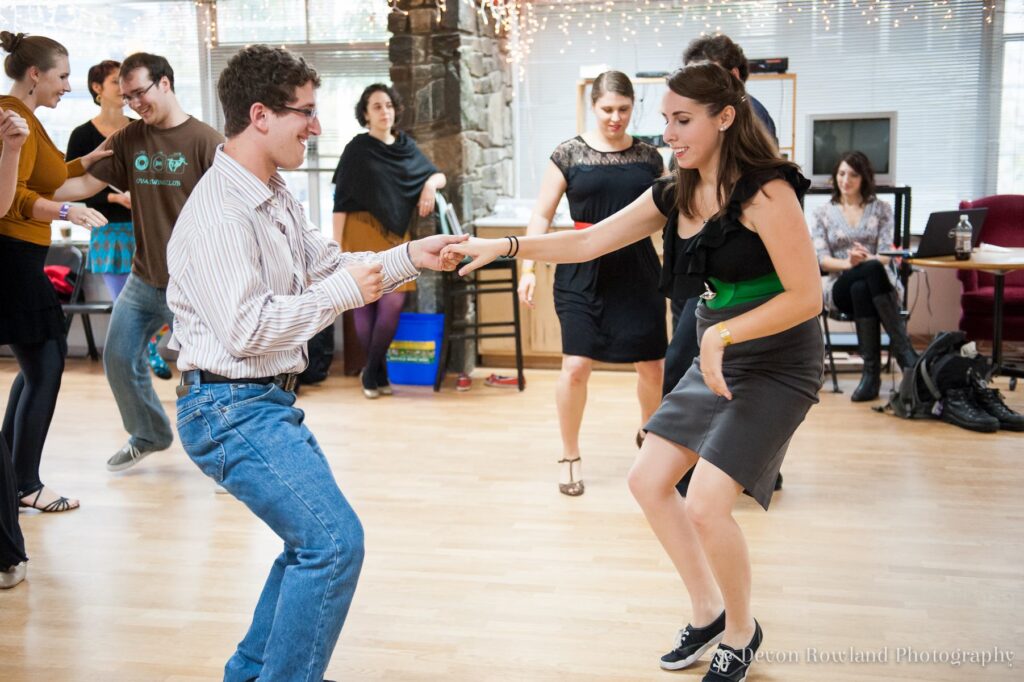 Several people dancing in pairs on a wooden floor