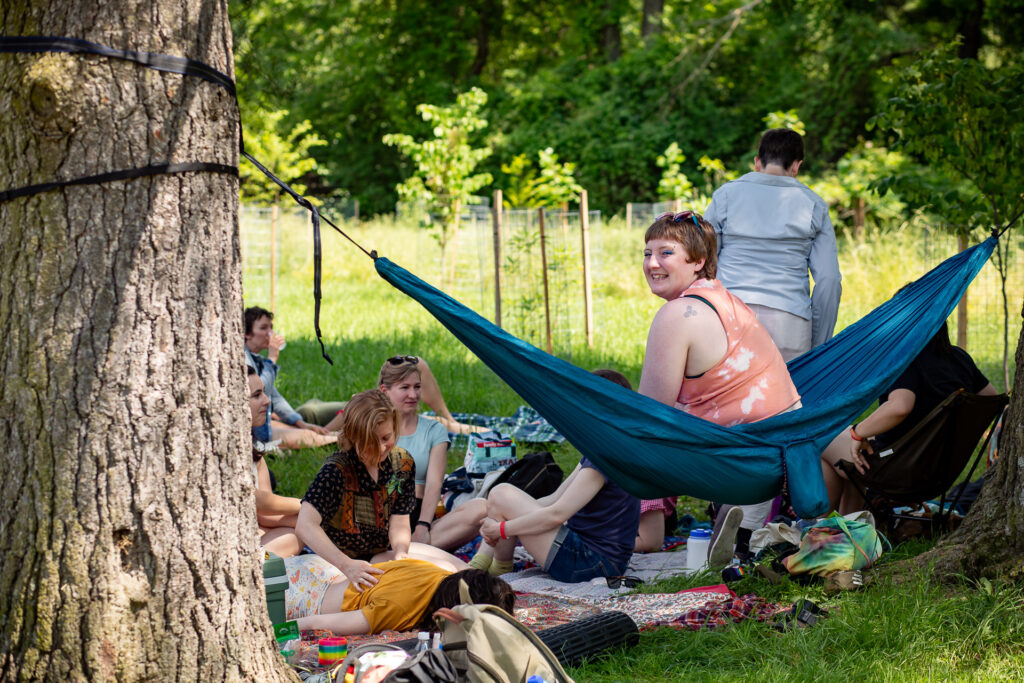 People sitting in hammock and on picnic blankets